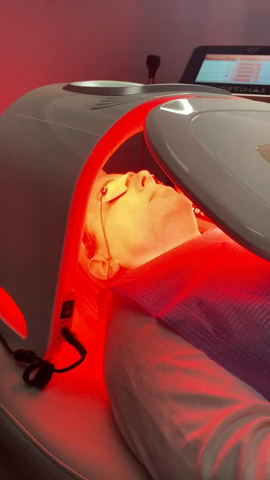A patient resting under a red LED light therapy panel